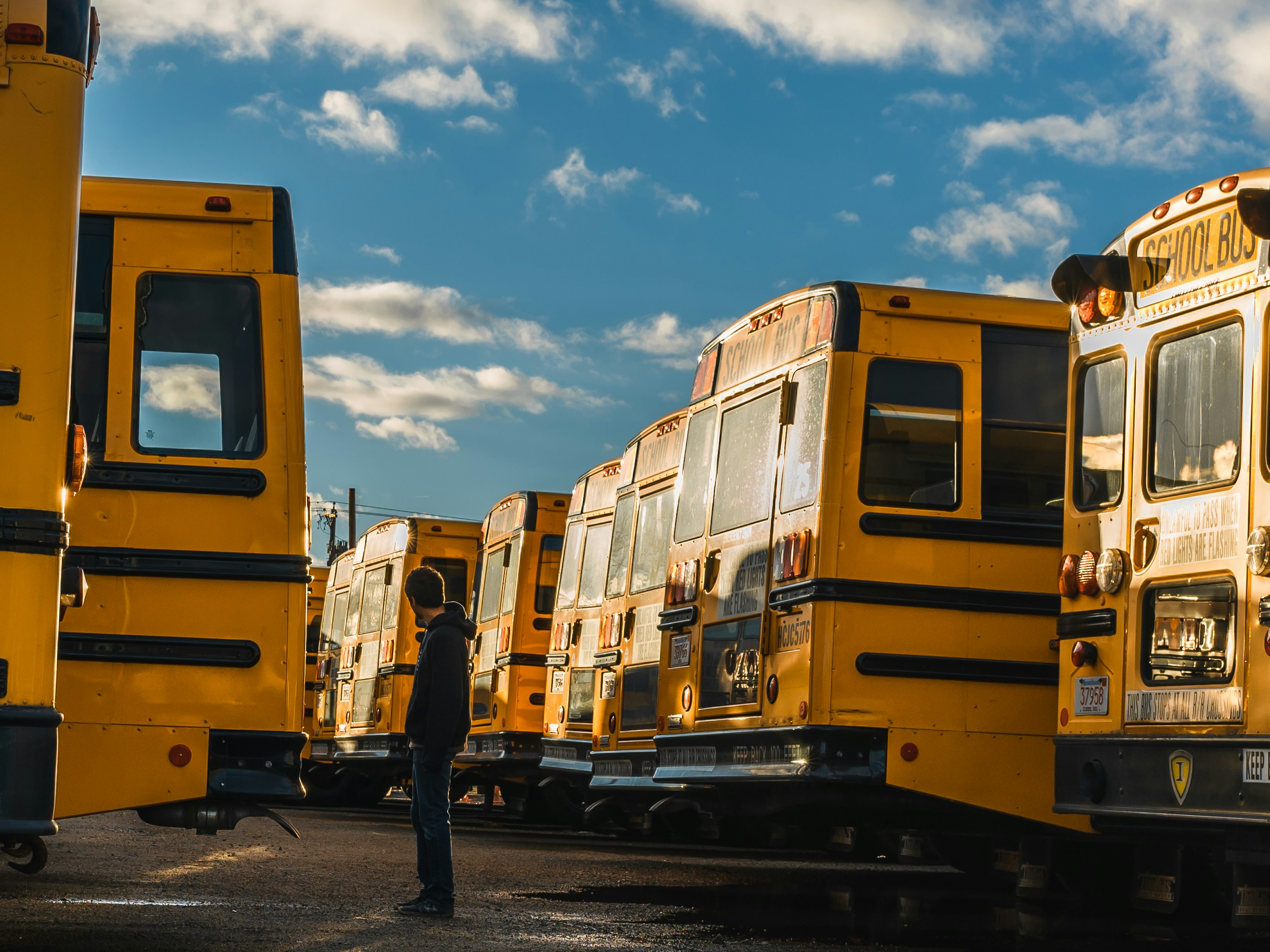 man standing between yellow bus during daytime
