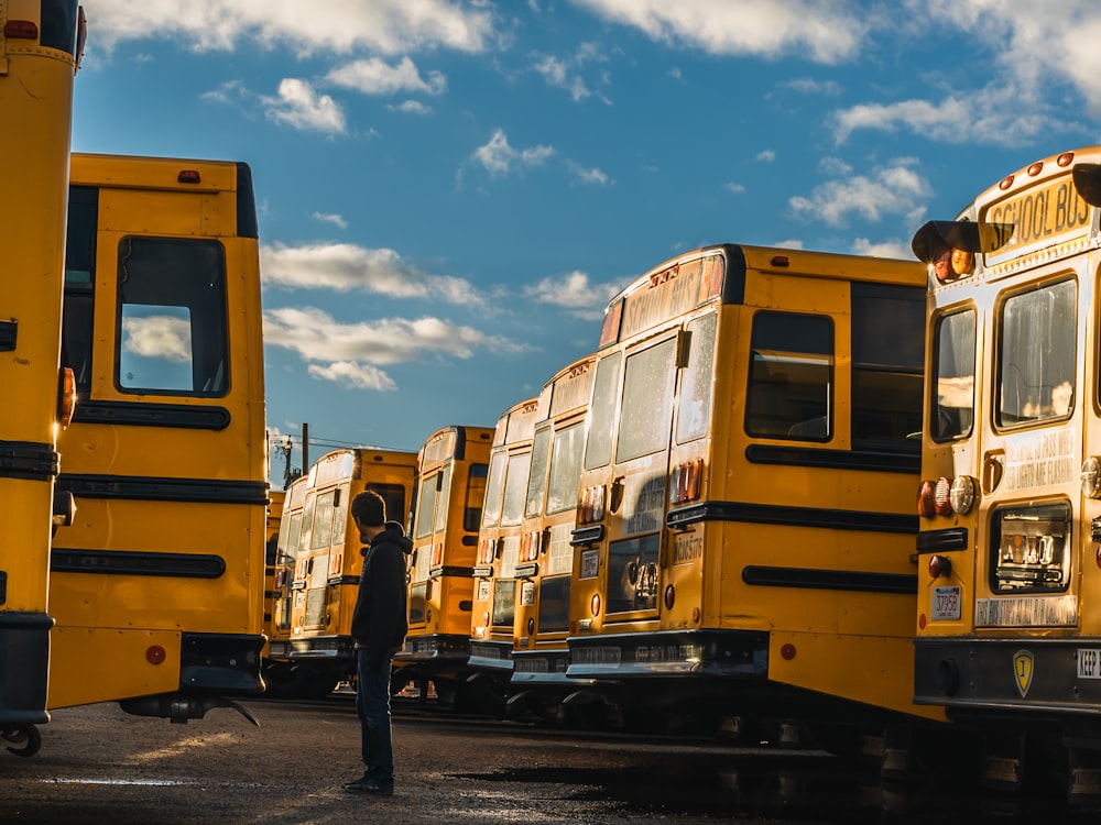 man standing between yellow bus during daytime