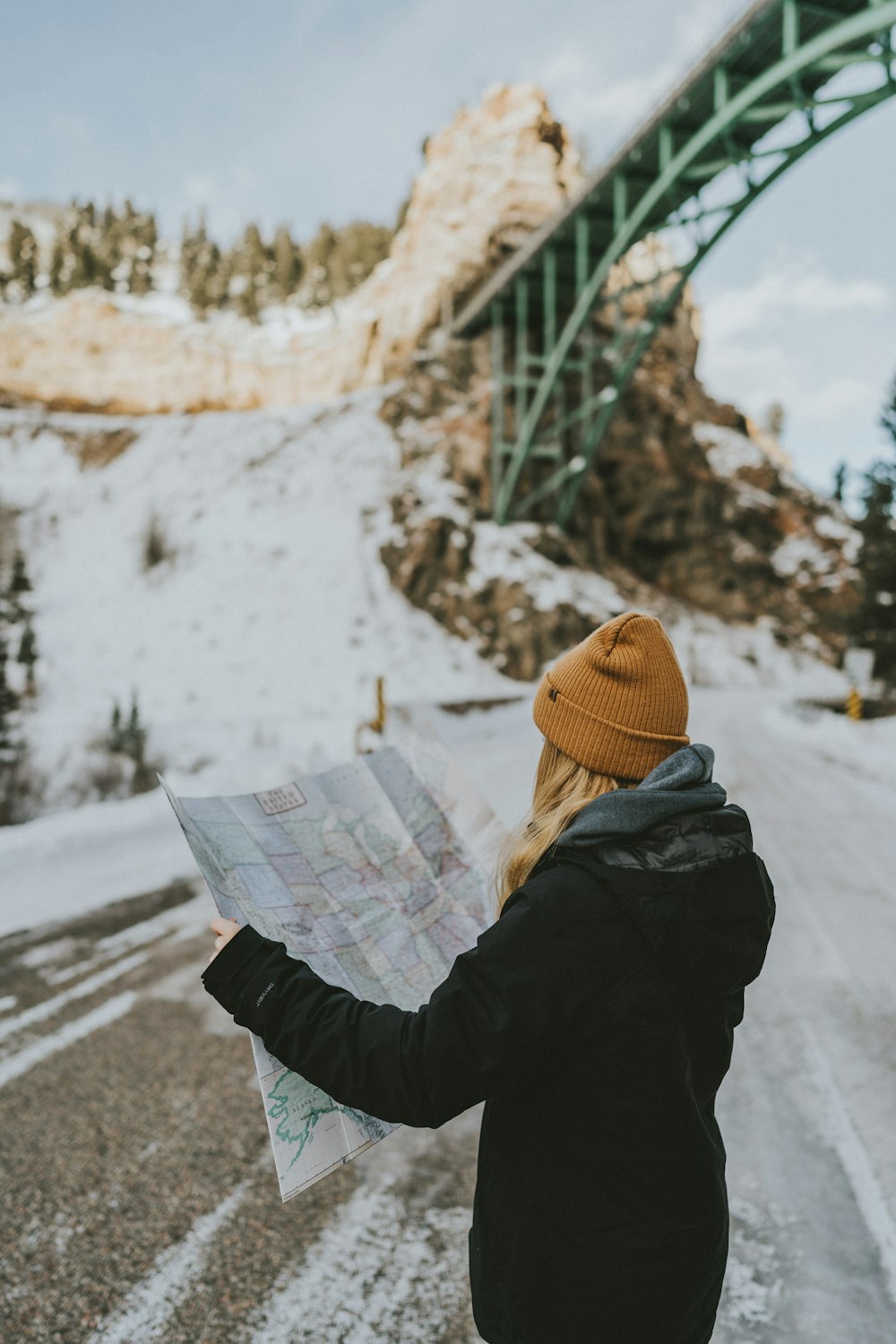 Donna in piedi sulla strada e che tiene la mappa durante il giorno