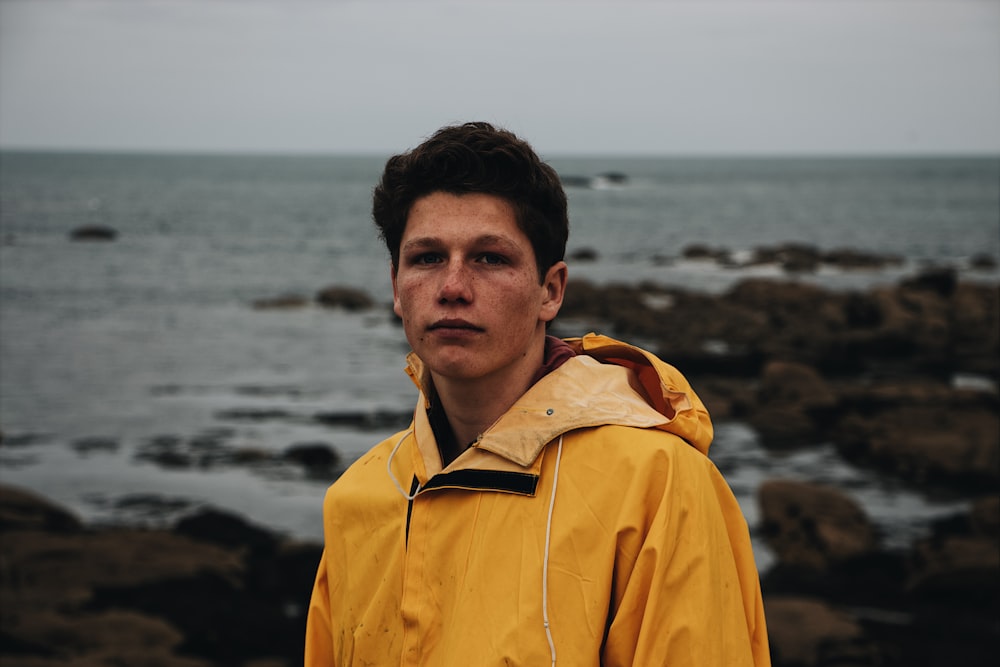 man in yellow jacket standing near sea during daytime