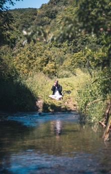 A serene scene of a person meditating outdoors surrounded by green herbs.