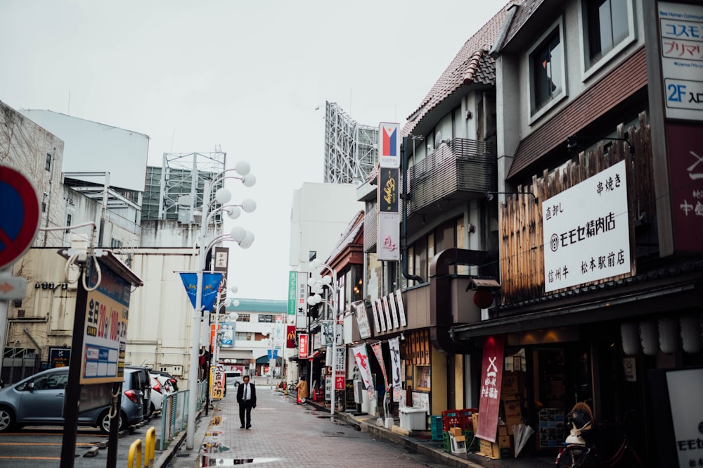 person walking on road beside stores