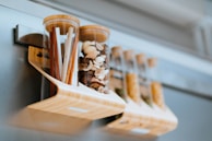 Organized spice jars and containers neatly lined up on a wooden rack.