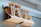 Close-up of a rustic hanging wall basket rack holding jars of spices in a bright kitchen.