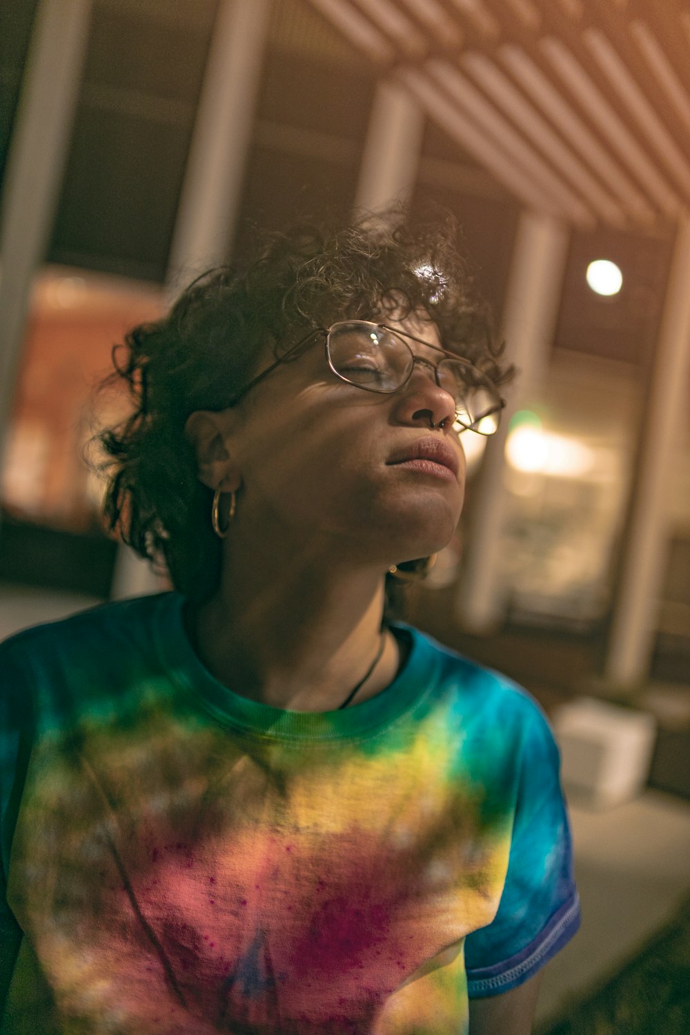 shallow focus photo of woman in tie-dyed T-shirt wearing eyeglasses with black frames