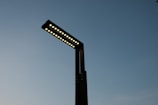 A modern street lamp with multiple LED lights extends into a clear evening sky, displaying a minimalist design with a sleek, dark silhouette.