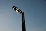 Close-up of a modern LED parking lot light fixture mounted on a tall pole against a clear evening sky.