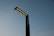 A modern street lamp with multiple LED lights extends into a clear evening sky, displaying a minimalist design with a sleek, dark silhouette.