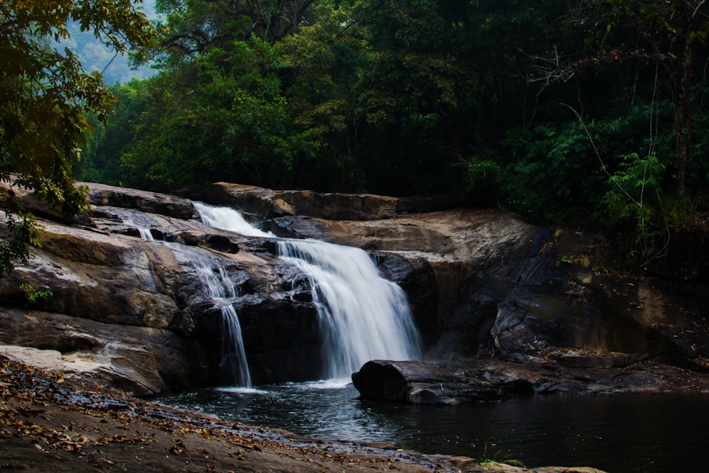 waterfalls in between trees during daytime