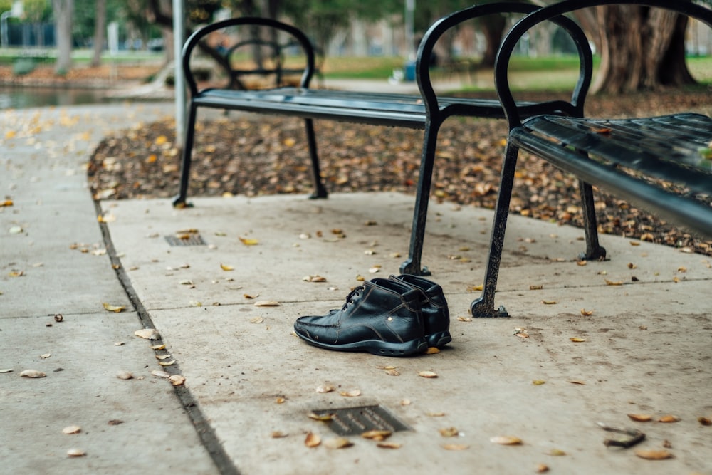 pair of black leather shoes near black metal benches