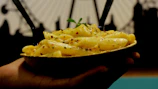 A student proudly holding a steaming bowl of one-pot pasta, smiling after a fast-paced cooking class.