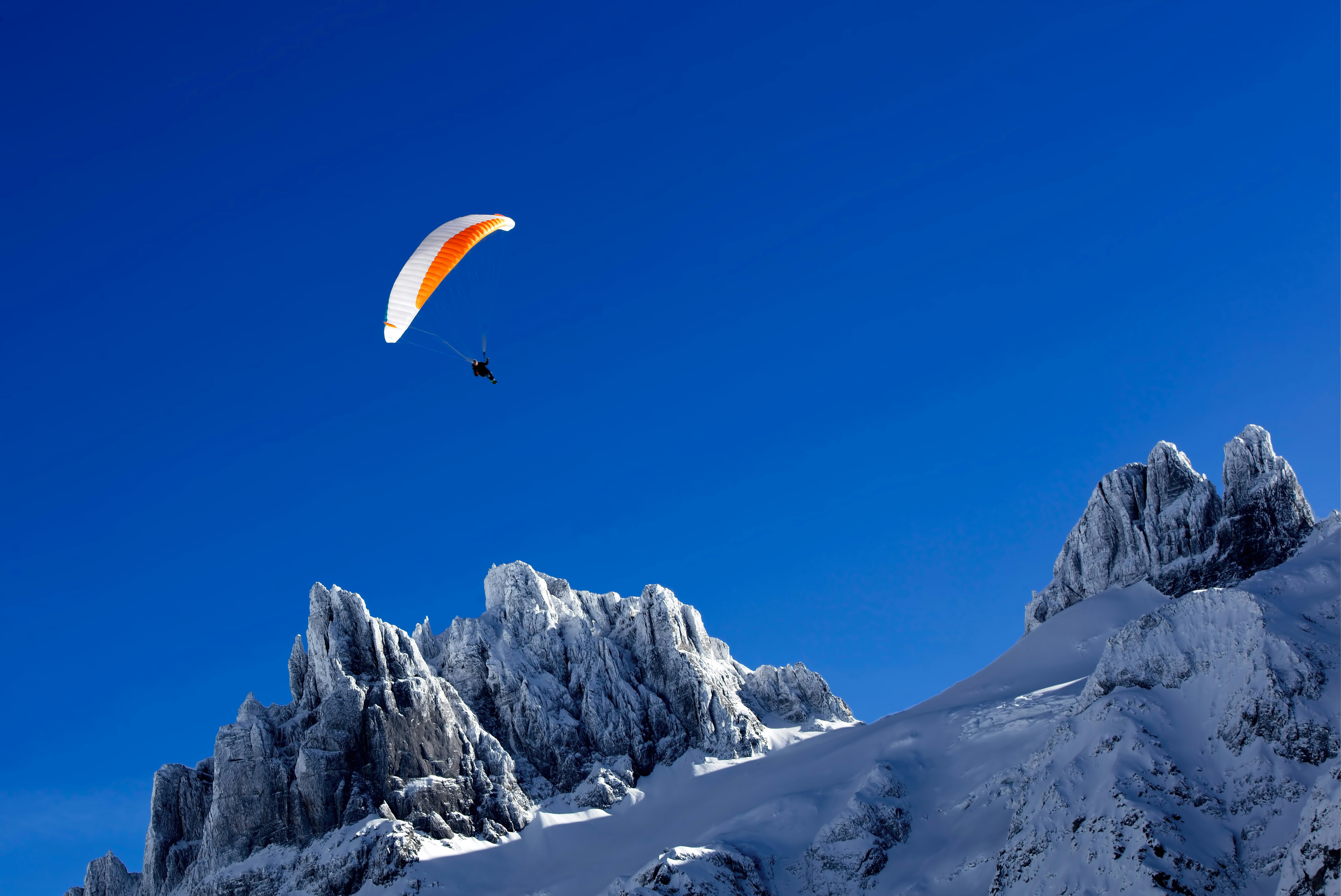 person paragliding above snow covered mountain during daytime