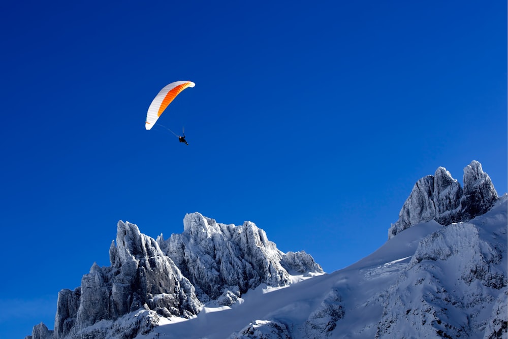 person paragliding above snow covered mountain during daytime