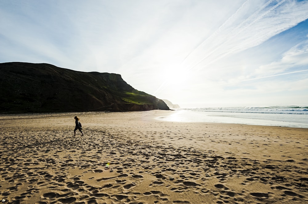 woman walking on brown beach sand