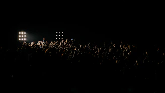 A shadowy crowd immersed in red and black lights beneath a glowing full moon, capturing the ritual's intense vibe.