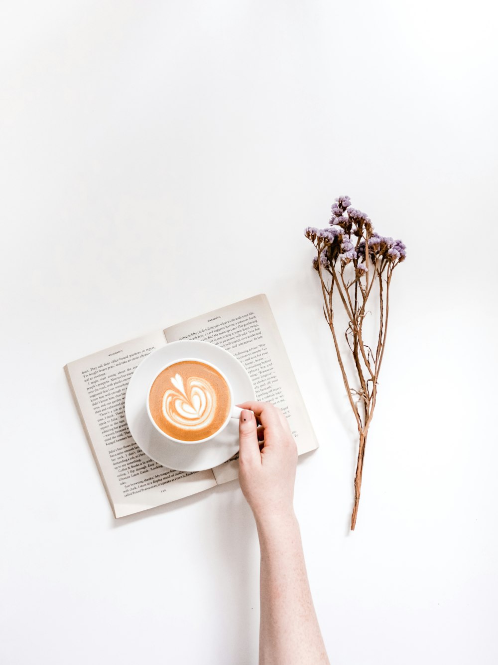 person holding cup of coffee on white table