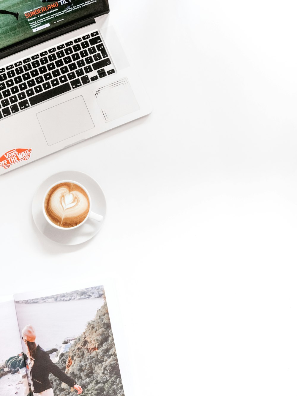 white teacup in saucer besides laptop computer