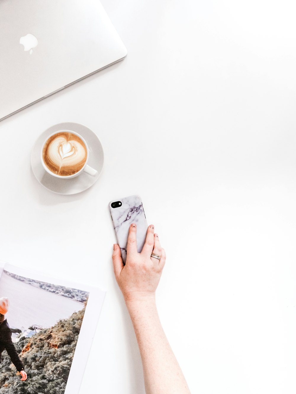 person holding smartphone near cup of coffee