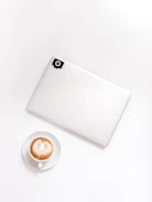 Minimalist photo of a laptop and coffee cup on a wooden desk.