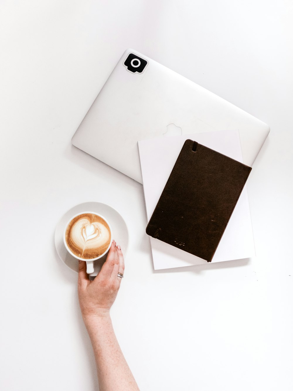 cappuccino beside closed MacBook