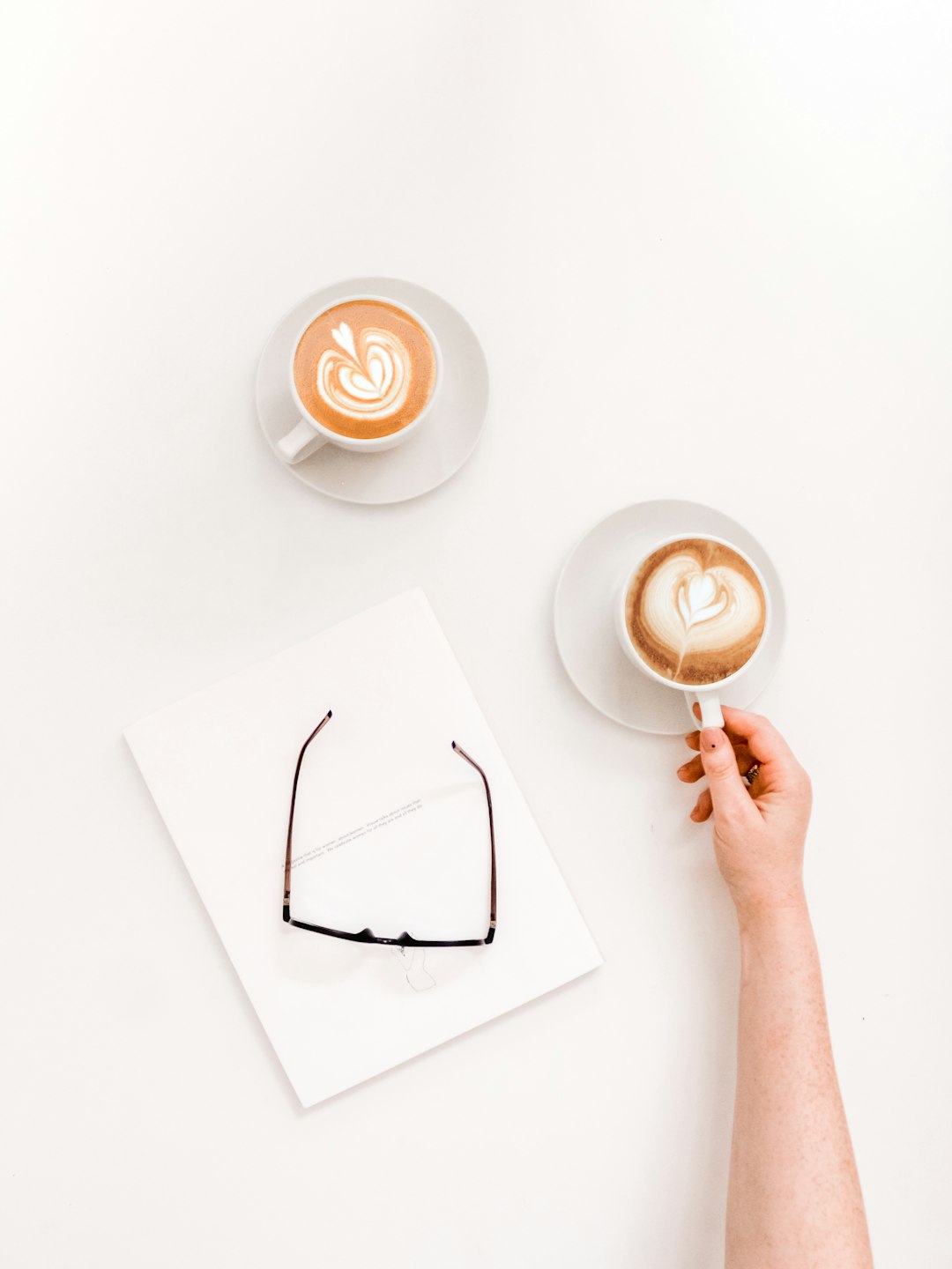 flat lay photography of person about to pick up cup of coffee latte