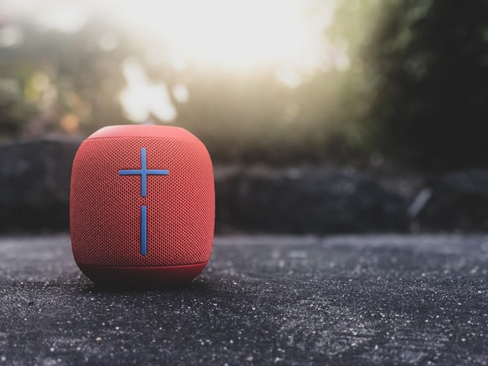 A sleek wireless Bluetooth speaker glowing softly on a wooden table.