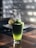 A vibrant glass of green smoothie garnished with fresh mint leaves on a wooden table.
