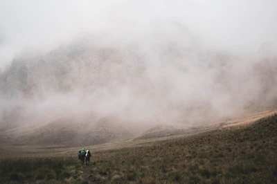 A group of travelers hiking through lush green hills of Ella with misty mountains in the background.