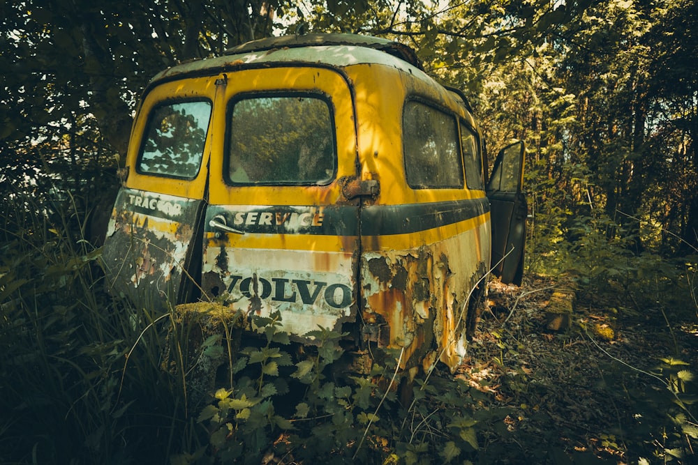 wrecked yellow Volvo minivan in forest