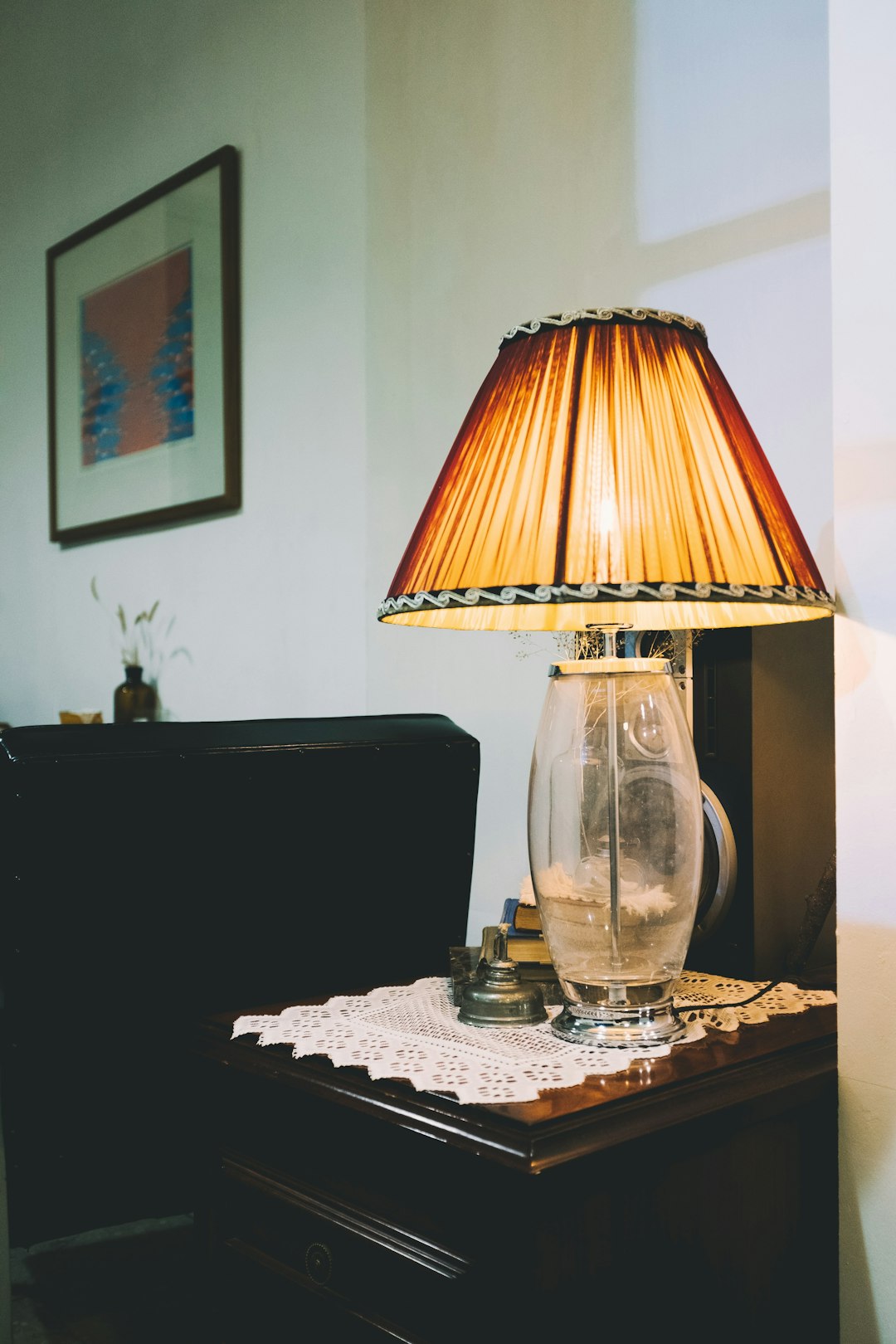 turned on clear glass table lamp on brown wooden end table
