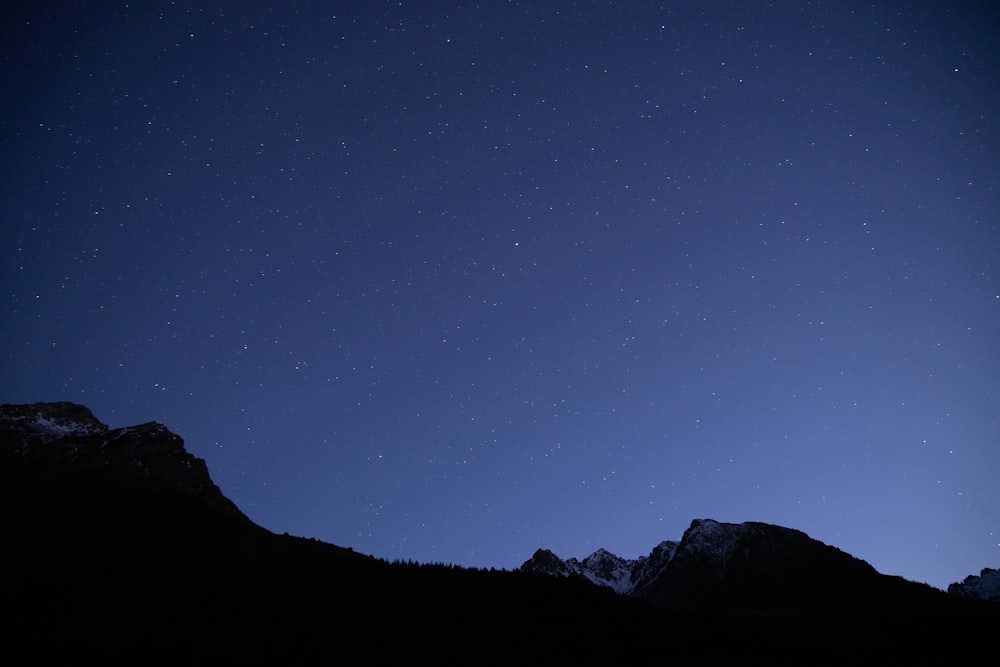 silhouette photography of mountain under calm blue sky during nighttime