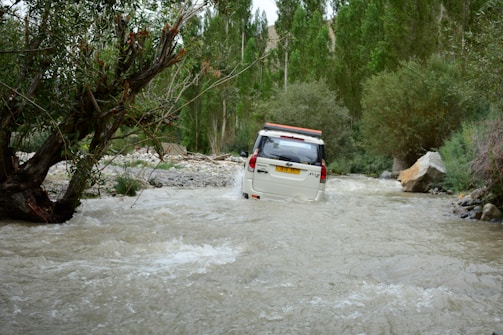 Tata Sierra SUV crossing a shallow stream in a forest trail.