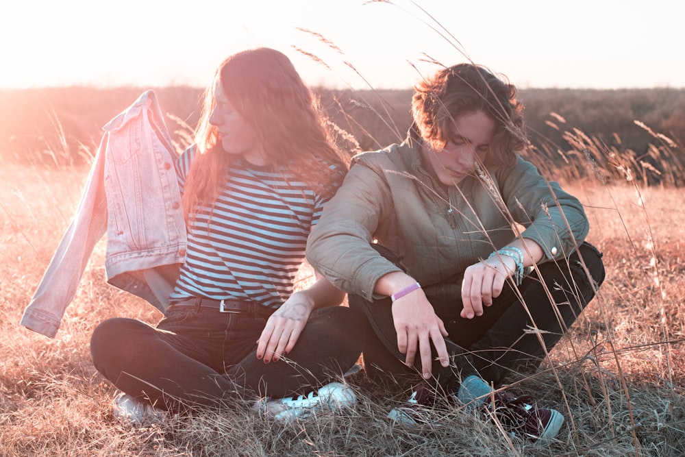 man and woman sitting on grass during golden hour