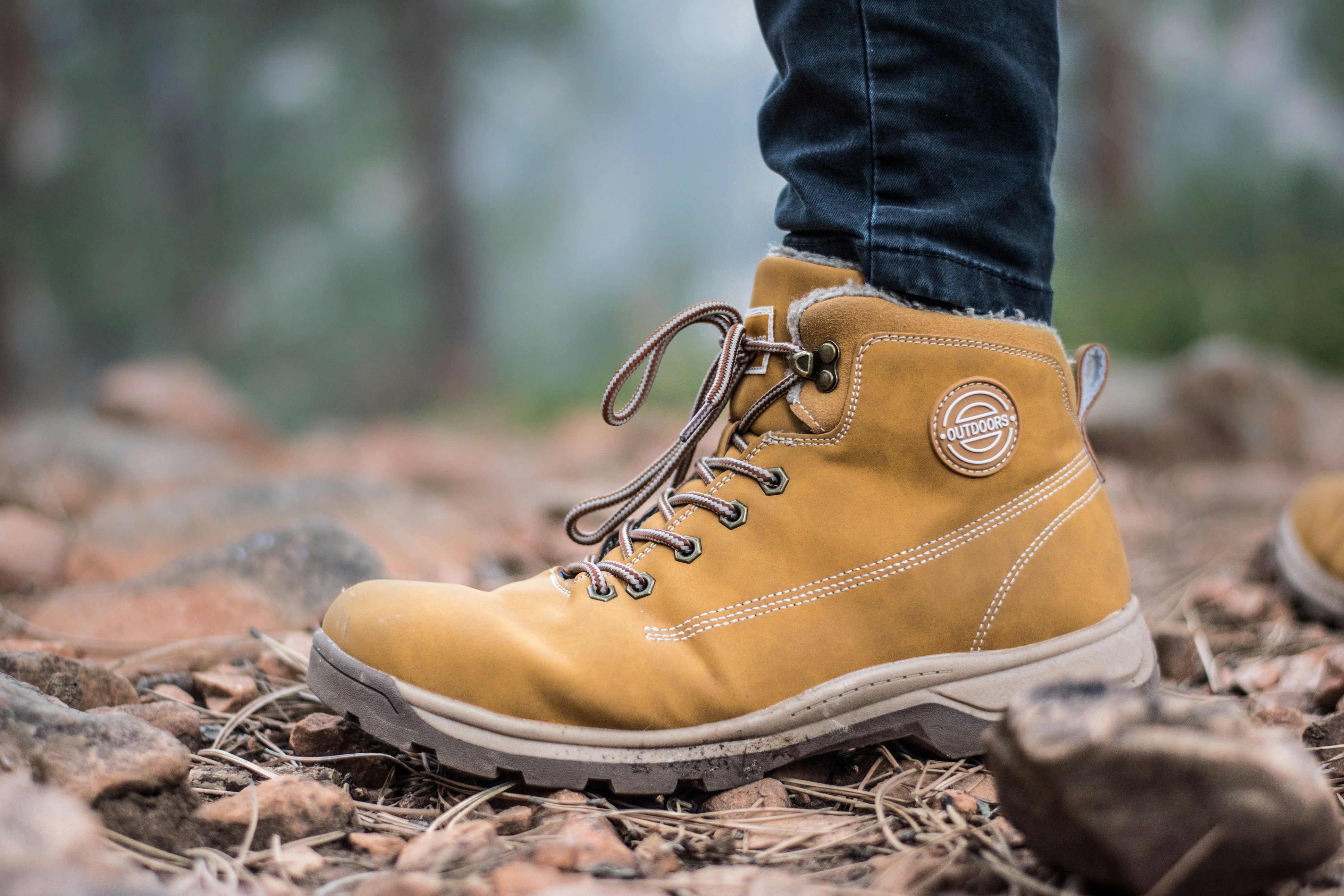 picture of a persons boots outdoors on fall leaves 
