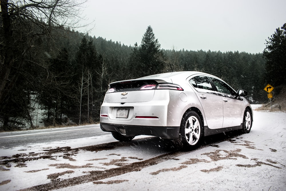 silver Chevrolet sedan on roadway near green leaf trees