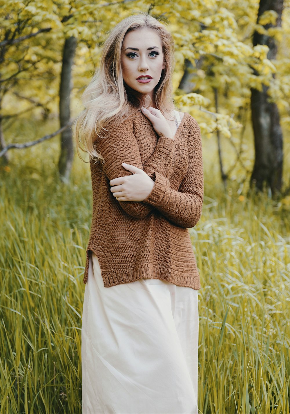 woman wearing brown sweater standing on green grass field