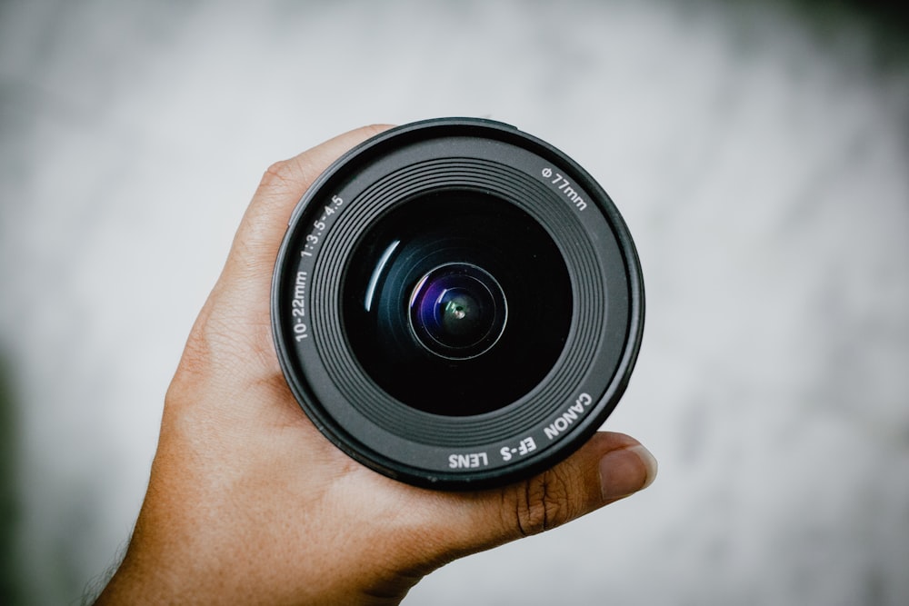 person holding black camera lens