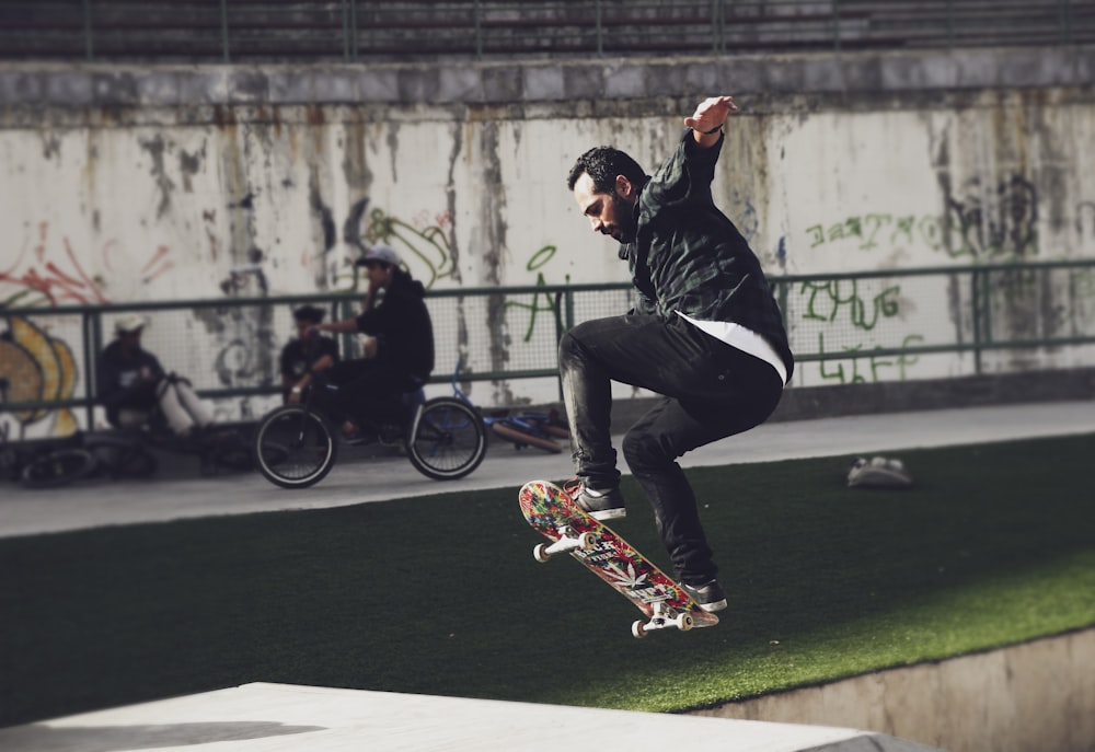 man wearing black jacket and black denim jeans with skateboard during daytime