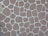 A textured stone wall pattern consisting of variously sized and shaped brown stones arranged in a mosaic with white grout lines between them.