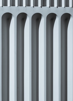 Vertical repeating geometric patterns with a series of elongated arches, creating a structured and symmetrical aesthetic. The shades of grey and blue suggest a focus on architecture or design.