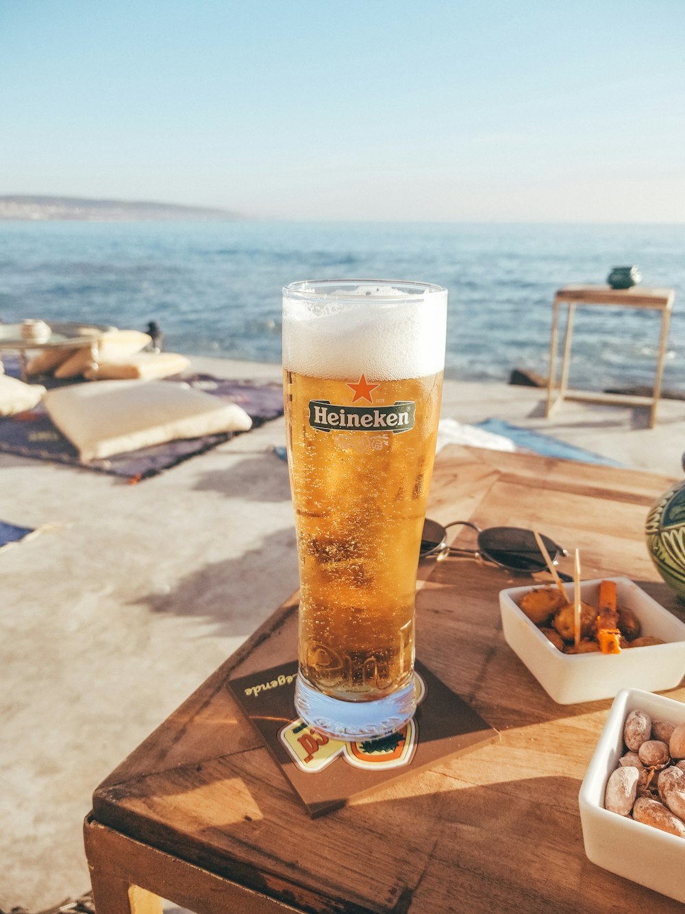 clear Heineken glass filled with yellow liquid on wooden table