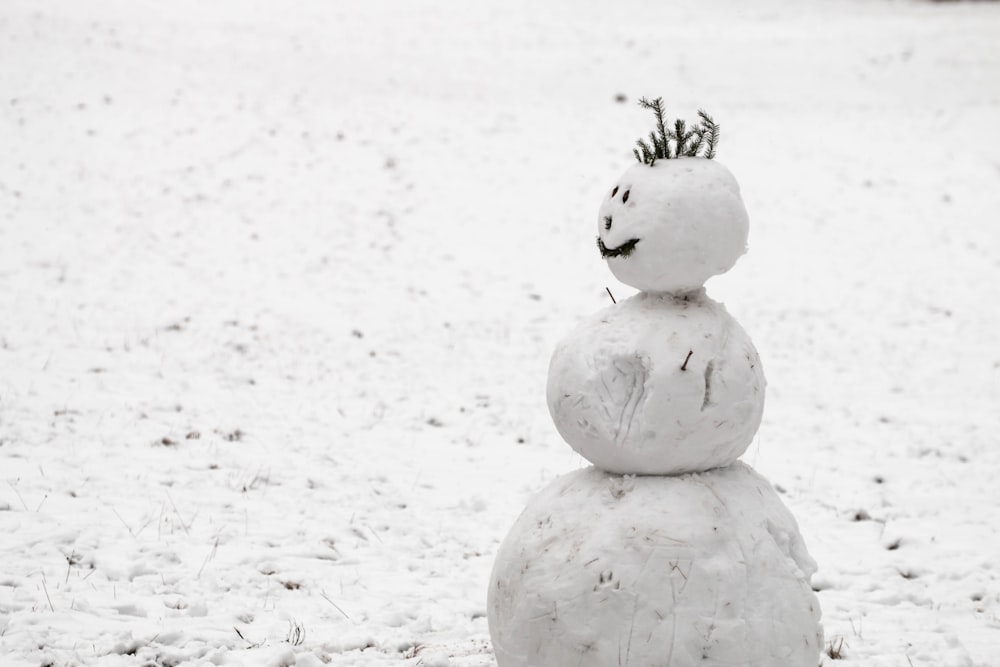 snow made snowman on snow covered field during daytime