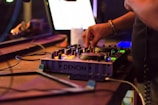 Close-up of hands adjusting knobs on a DJ mixer during a live set.