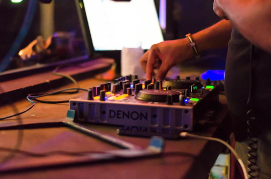 Close-up of a music producer adjusting knobs on a mixing console in a dimly lit studio.