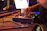 A DJ adjusting knobs on a synthesizer in a dimly lit studio with urban industrial design.