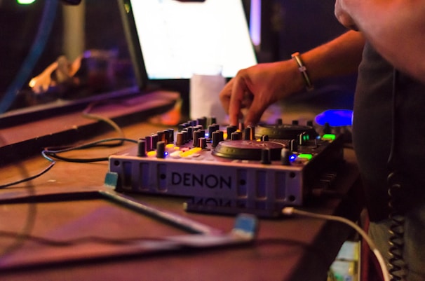 Close-up of a DJ's hands adjusting the mixer knobs in a dark club.