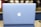 A sleek, silver laptop displaying a prominent glowing apple logo on its lid, set against a blurred background with soft lighting.