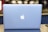A sleek, silver laptop displaying a prominent glowing apple logo on its lid, set against a blurred background with soft lighting.