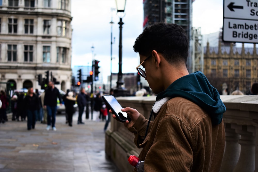 man standing and using phone near people