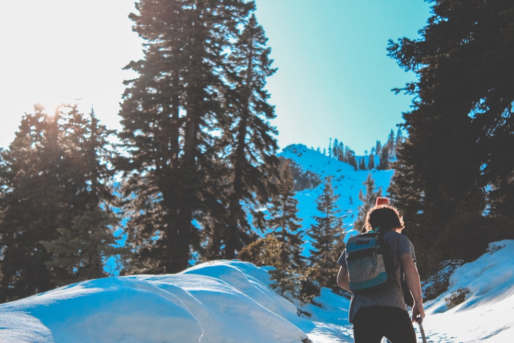 man waking on snow ground while carrying backpack